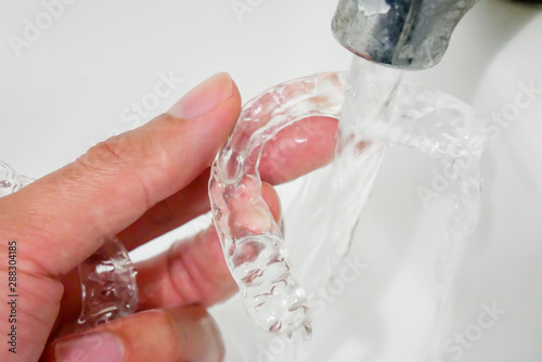 hand holding clear plastic retainer teeth that isolated on blue sky background. it's an equipment for orthodontist give the patient to orthodontic surgery in dental clinic or hospital