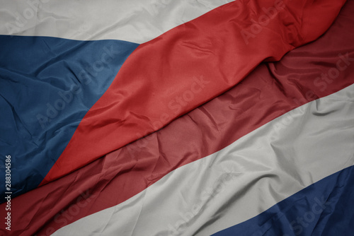 waving colorful flag of netherlands and national flag of czech republic.