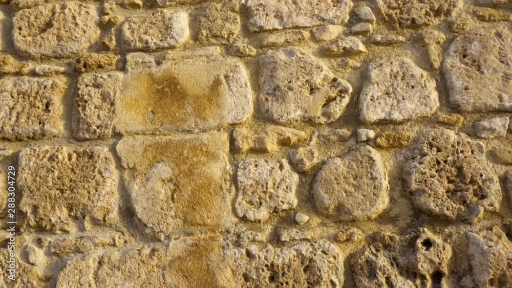 First person POV walking in old city looking at rustic ancient stone wall. Close up european city yellow rocky stones church exterior. Camera trucking First person POV walking in old city looking at rustic ancient stone wall. Close up european city yellow rocky stones church exterior. Camera trucking