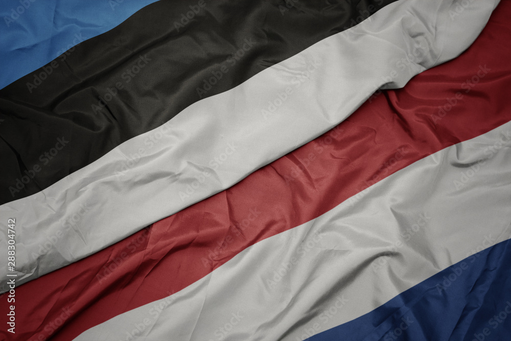 waving colorful flag of netherlands and national flag of estonia. waving colorful flag of netherlands and national flag of estonia.