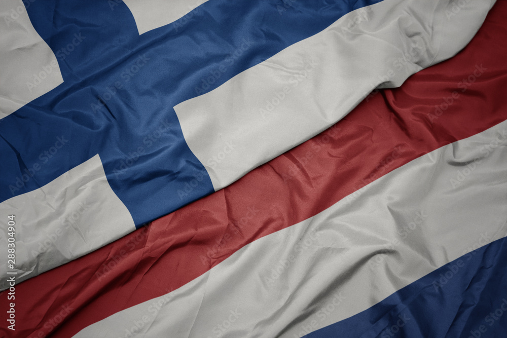 waving colorful flag of netherlands and national flag of finland. waving colorful flag of netherlands and national flag of finland.