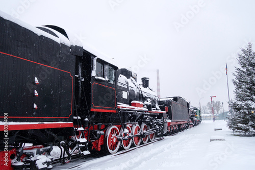 Steam train in snow. Soviet black and red locomotive. Steam engine transport.
