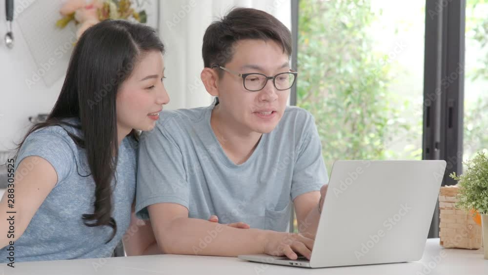 Young Asian couple using laptop computer for shopping searching online at home Young Asian couple using laptop computer for shopping searching online at home