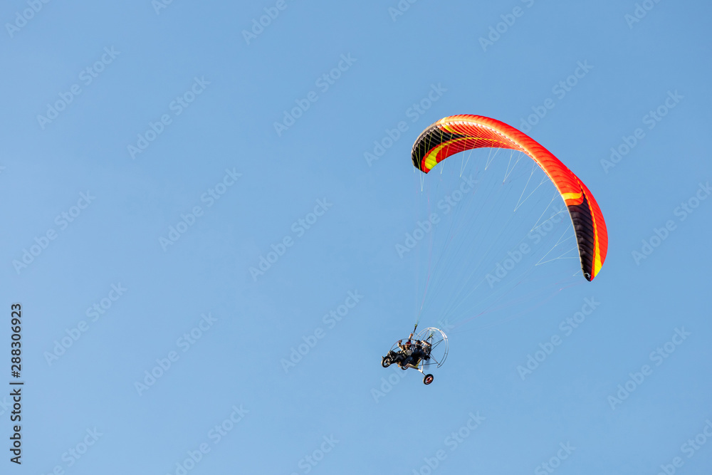 bright paraglider with a motor flies in the blue sky bright paraglider with a motor flies in the blue sky