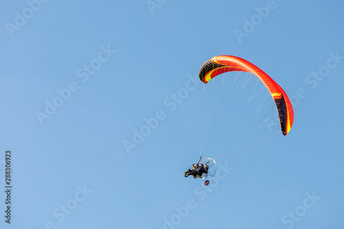 bright paraglider with a motor flies in the blue sky
