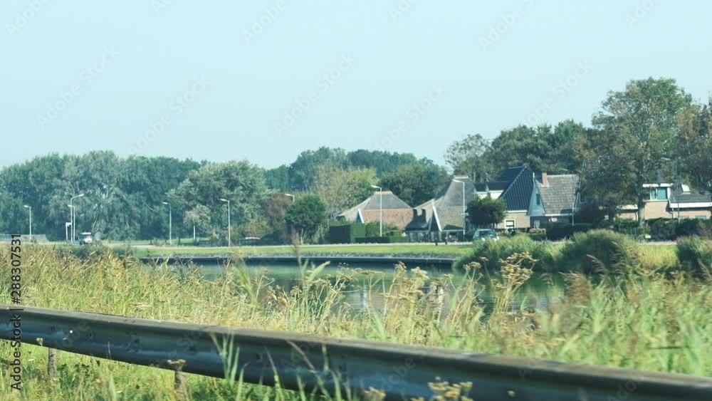 Driving along Dutch canal with cute rural houses in Netherlands Driving along Dutch canal with cute rural houses in Netherlands