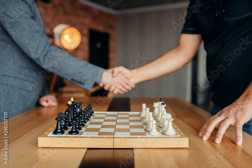 Male chess players shake hands before the game