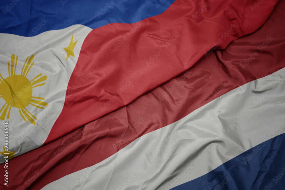 waving colorful flag of netherlands and national flag of philippines. waving colorful flag of netherlands and national flag of philippines.