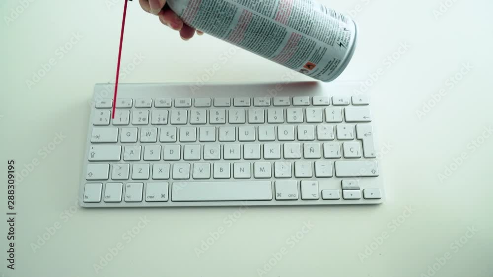 Dusting white keyboard with compressed air spray, White Background