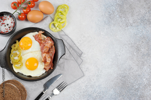 Fried eggs with bacon in a pan. Light background. View from above. Free space for text.