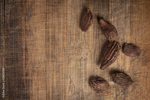 MACRO SHOT OF BLACK CARDAMOM ON WOODEN TEXTURE BACKGROUND, GARAM MASALA 