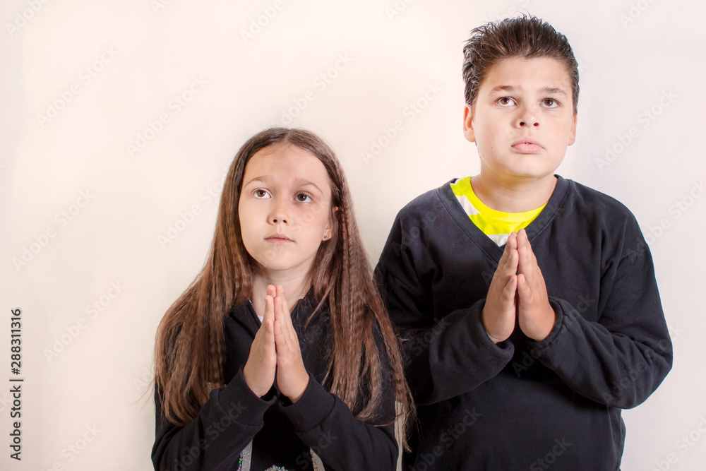 A little girl and a boy pray. Children ask for something