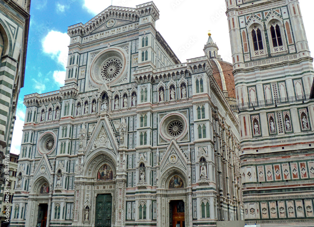 Florence Cathedral, Italy. Basilica of Santa Maria del Fiore (Duomo di Firenze) and bell tower (Giotto's Campanile) on the piazza del Duomo. Ornate marble facade of building exterior.