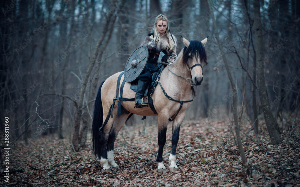 Viking warrior female ridding a horse at twilight autumn forest