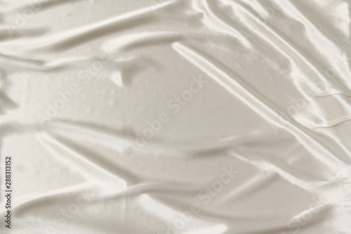 white beautiful satin fabric draped with soft folds, silk cloth background, close-up, copy space