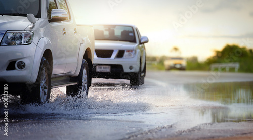 Cars run through flood water after hard rain with water spray from the wheels .Stop action ( capture with the high speed shutter) and selective focus.