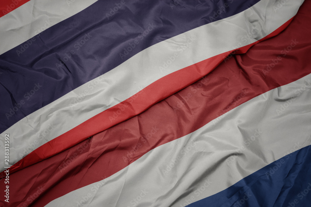 waving colorful flag of netherlands and national flag of thailand. waving colorful flag of netherlands and national flag of thailand.