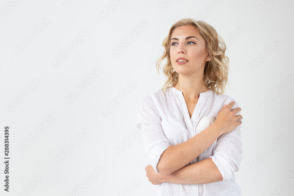 Cheerful young blond woman with long curly hair posing on a white background with copy space. The concept of a beautiful and well-groomed woman