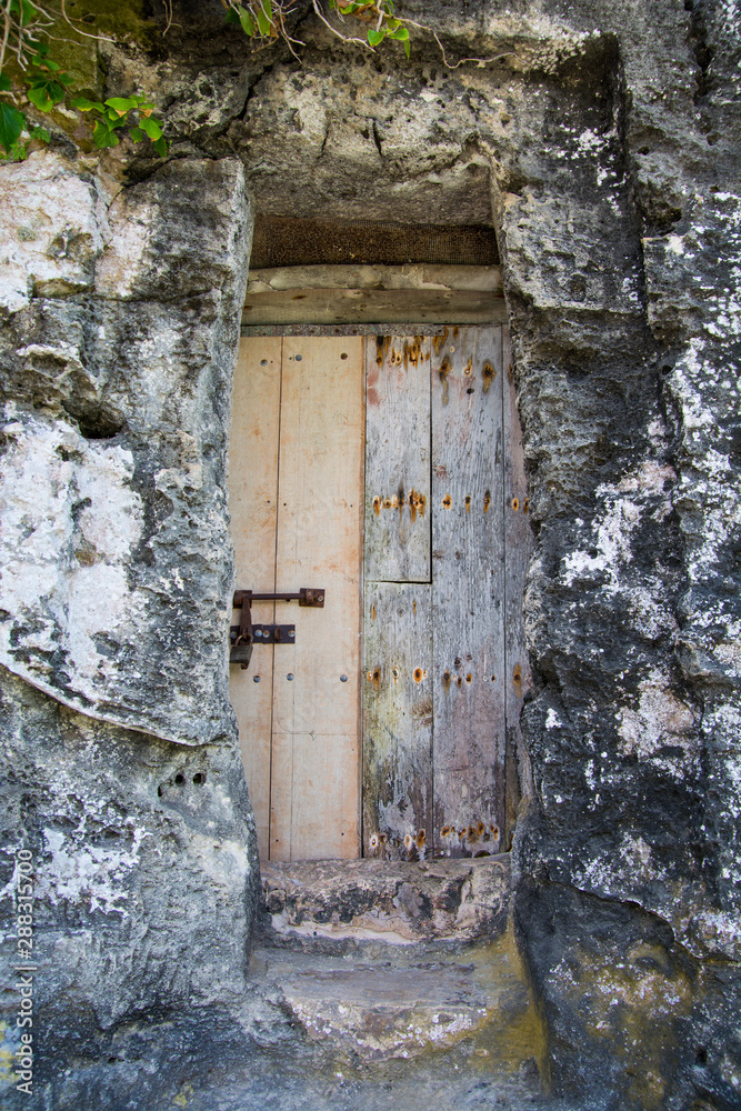 Old and weathered wooden door at the entrance of a cave Old and weathered wooden door at the entrance of a cave