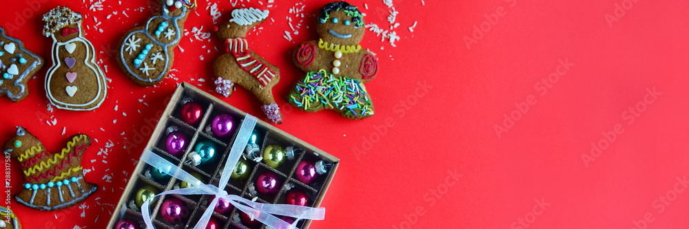Red christmas card panorama background with gingerbread man and christmas balls. Holidays mood with gift and copy space.