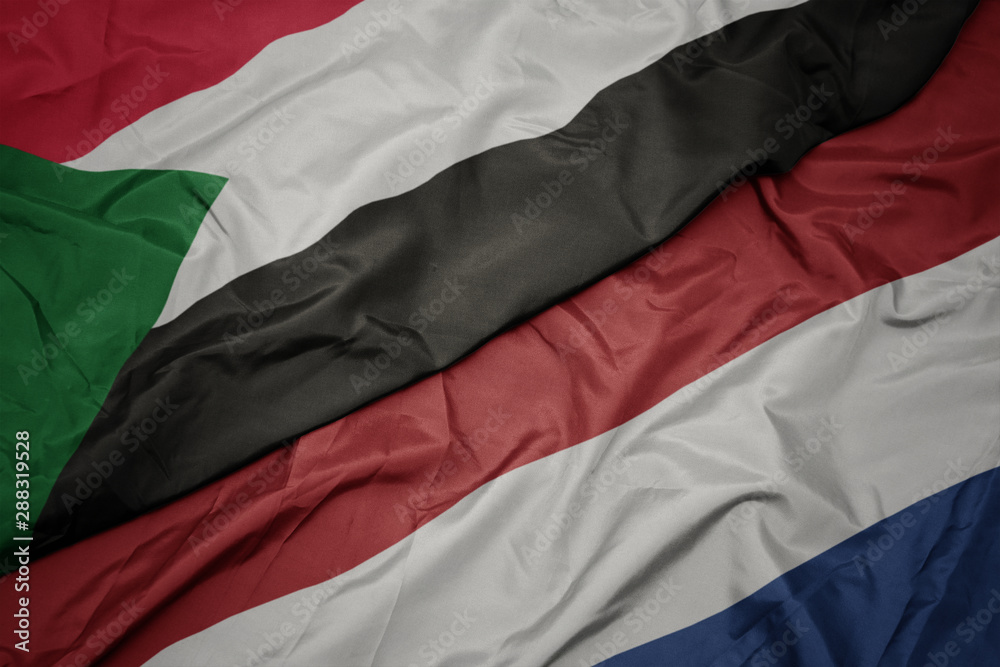 waving colorful flag of netherlands and national flag of sudan. waving colorful flag of netherlands and national flag of sudan.