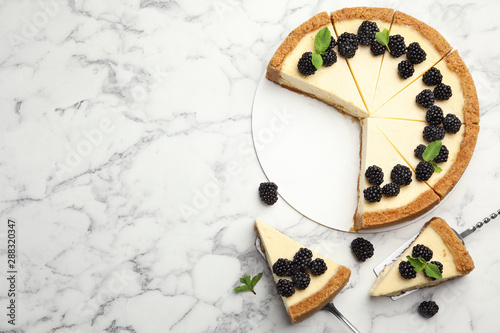 Sliced delicious cheesecake with blackberries on white marble background, flat lay. Space for text photo