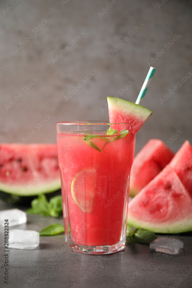 Glass of tasty refreshing drink with watermelon on grey table Glass of tasty refreshing drink with watermelon on grey table