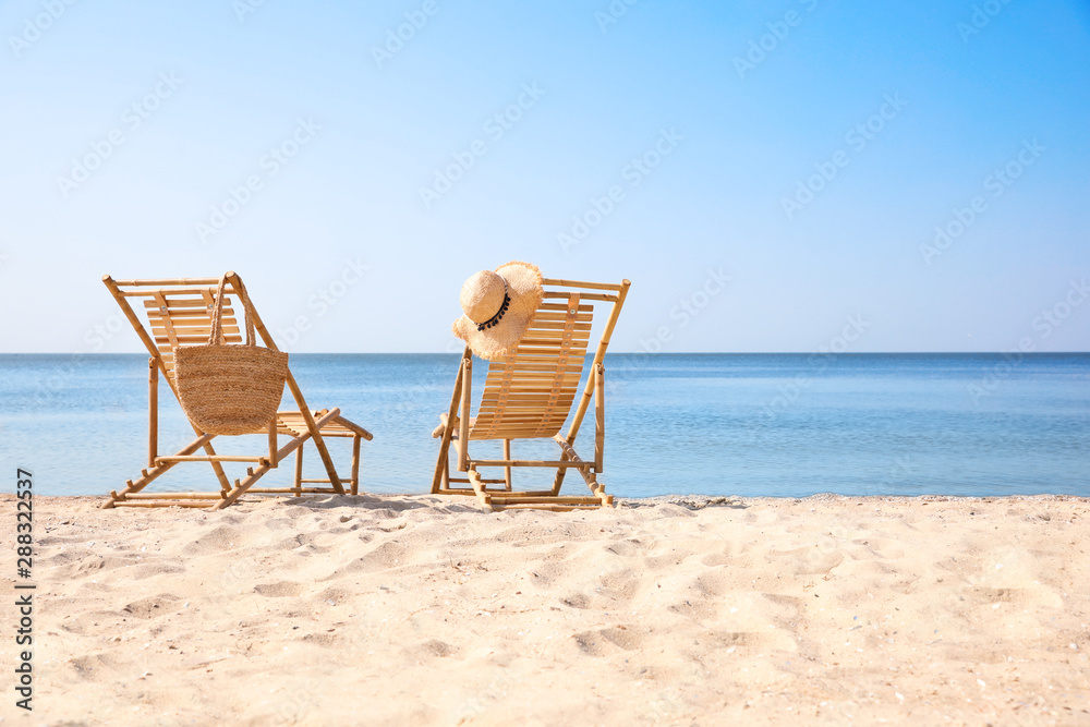 Wooden deck chairs on sandy beach near sea