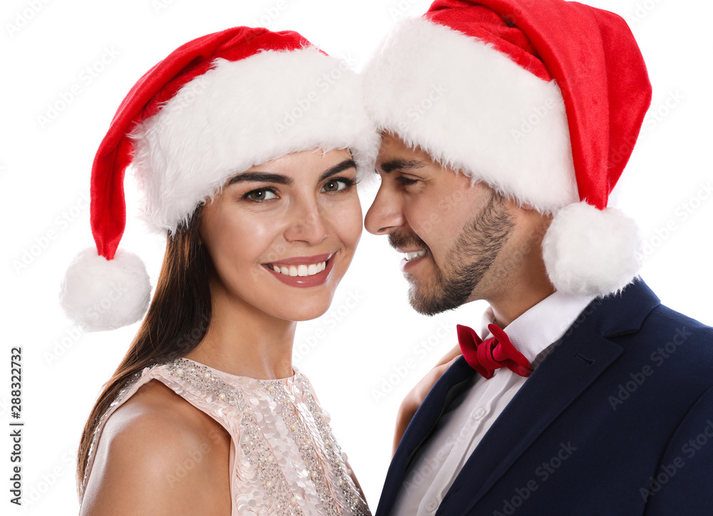 Lovely young couple in Santa hats on white background. Christmas celebration Lovely young couple in Santa hats on white background. Christmas celebration