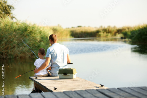 Dad and son fishing together on sunny day. Space for text