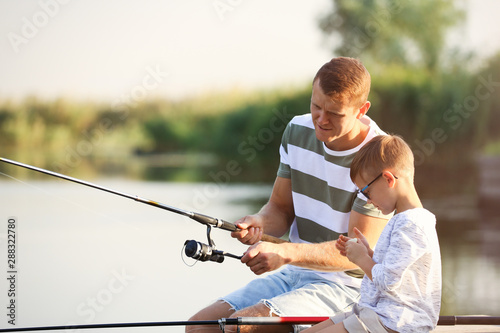 Dad and son fishing together on sunny day