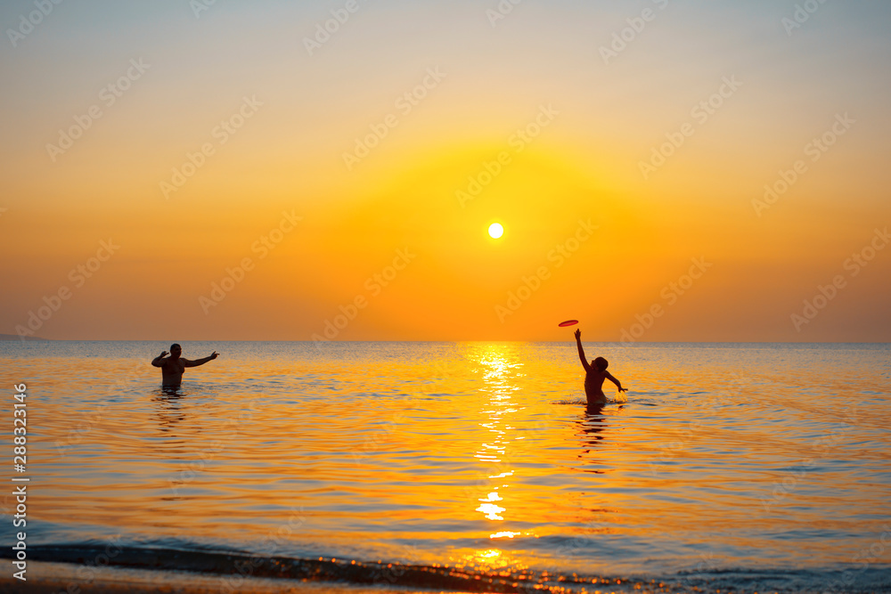 Two People in sea at sunset