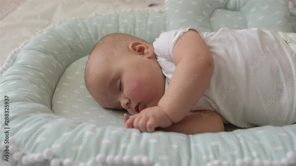 Baby is sleeping on the bed. Mom covers with a blanket.