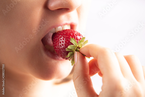 Closeup of a woman mouth eating strawberry. 