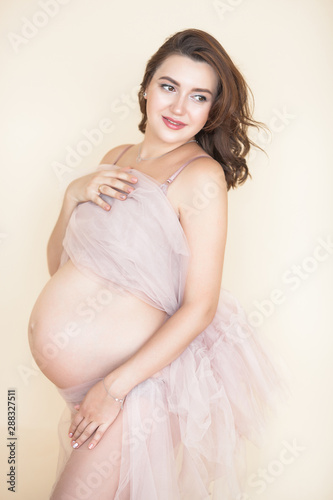 Beautiful pregnant woman on neutral background. Expectant closeup picture. Future mother portrait on pastel background.