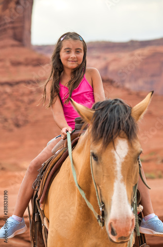 Happy young girl riding horse in Monument Valley