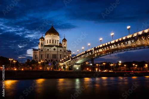 Illuminated Cathedral of Christ the Savior framed with old style street lights of Patriarchy Bridge at night.