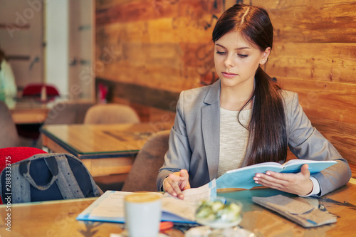 schoolgirl in a cafe reading a textbook preparing for exams