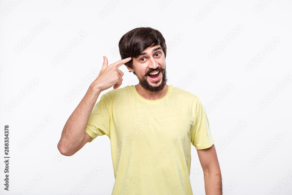 Young brunet bearded man with mustache joyfully showing at his head as if he has mass of task to do. Young brunet bearded man with mustache joyfully showing at his head as if he has mass of task to do.