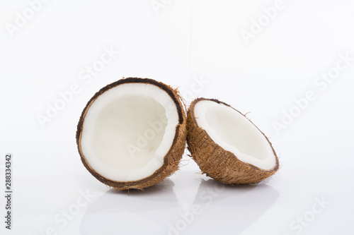 Coconut shell and grated coconut flakes on a brown wooden board isolated on white background.