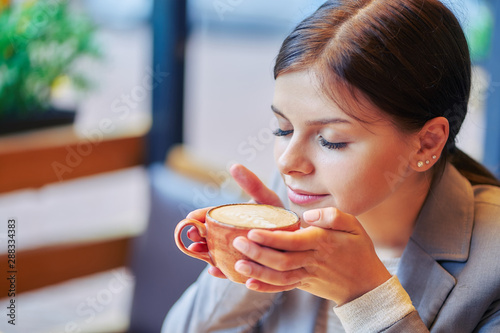 young girl enjoys the smell of coffee in a cafe