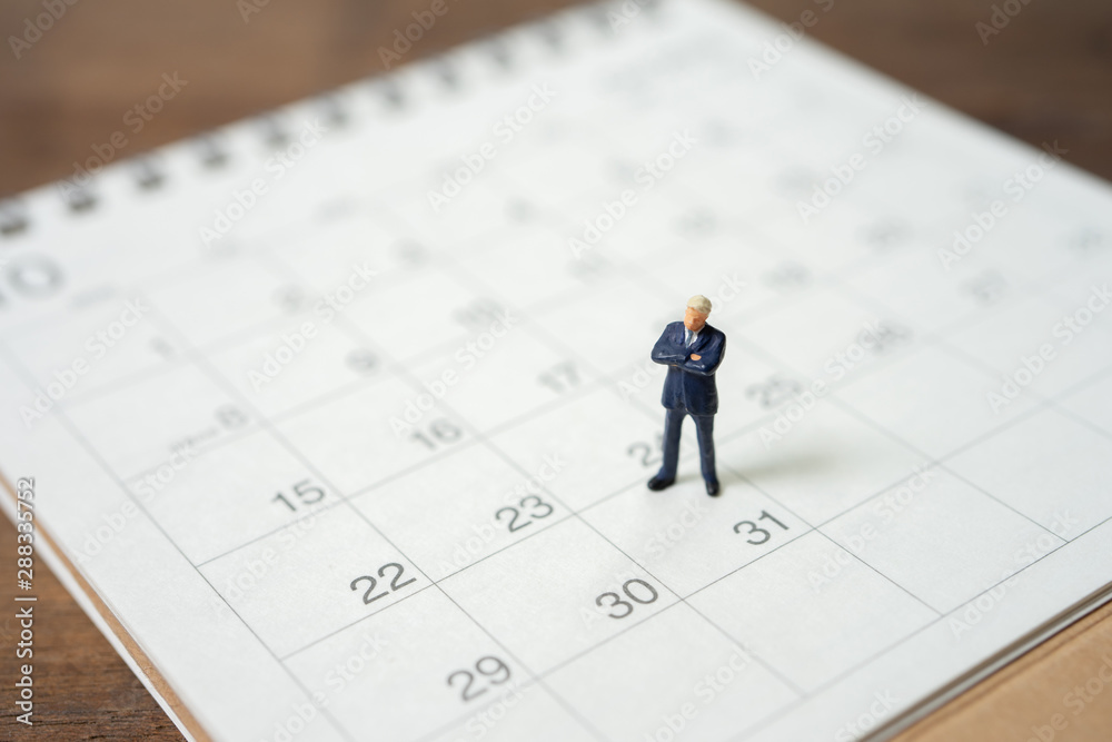 Miniature people businessmen standing on white calendar using as background business concept and finance concept with copy space for your text or design. Miniature people businessmen standing on white calendar using as background business concept and finance concept with copy space for your text or design.