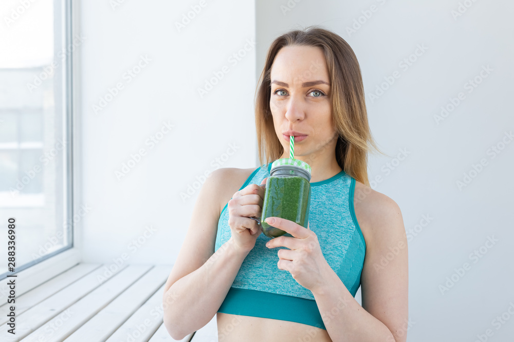 Healthy, diet, detox and weight loss concept - close-up of young woman in sportswear with green smoothie Healthy, diet, detox and weight loss concept - close-up of young woman in sportswear with green smoothie