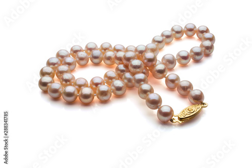 A single strand necklace of Pink pearls with a gold clasp are crossed over itself. Shown on a white background with shadow.