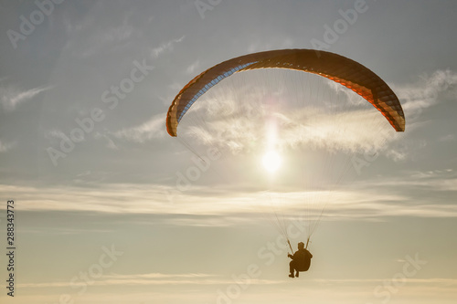 Paraglide with a paraglider in a cocoon against the background of fields of the sky and clouds. Paragliding Sports