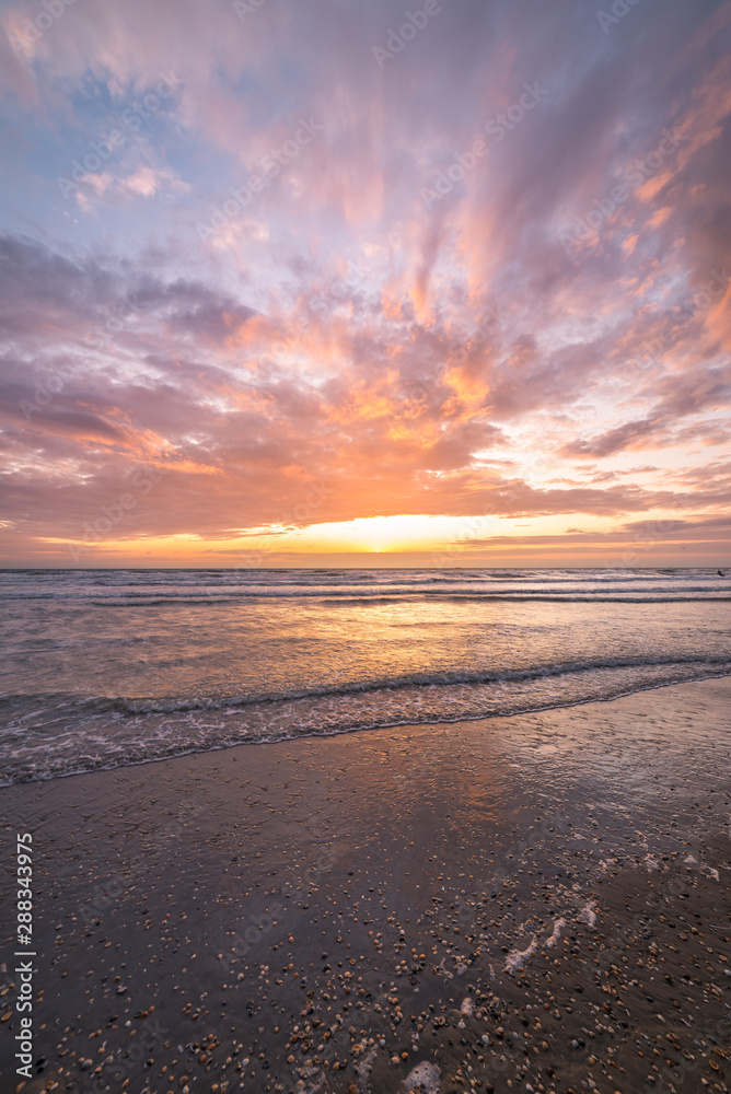 Colorful clouds at the dutch coast as the sun sets below the horizon