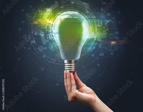 Hand holding light bulb on dark background. New business idea concept