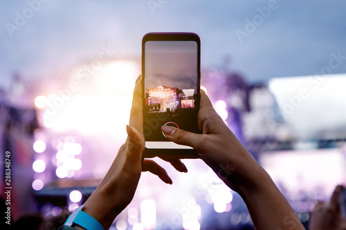 A girl is taking pictures of a street concert on the phone. photo