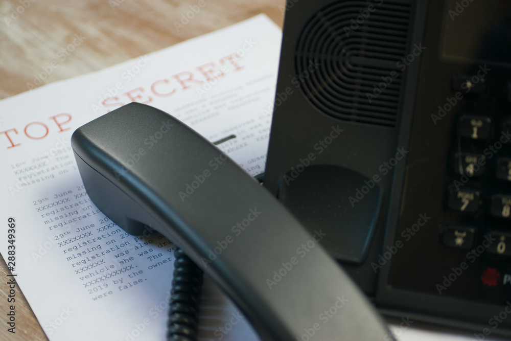 Top secret document containing classified information with black desk phone