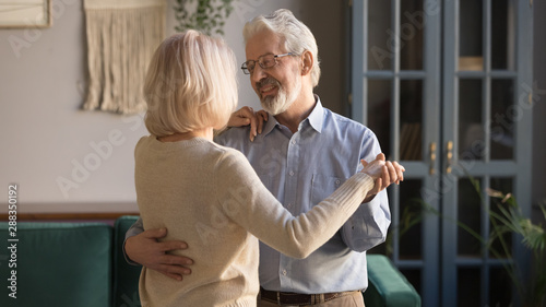 Elderly couple enjoy time together dancing at home